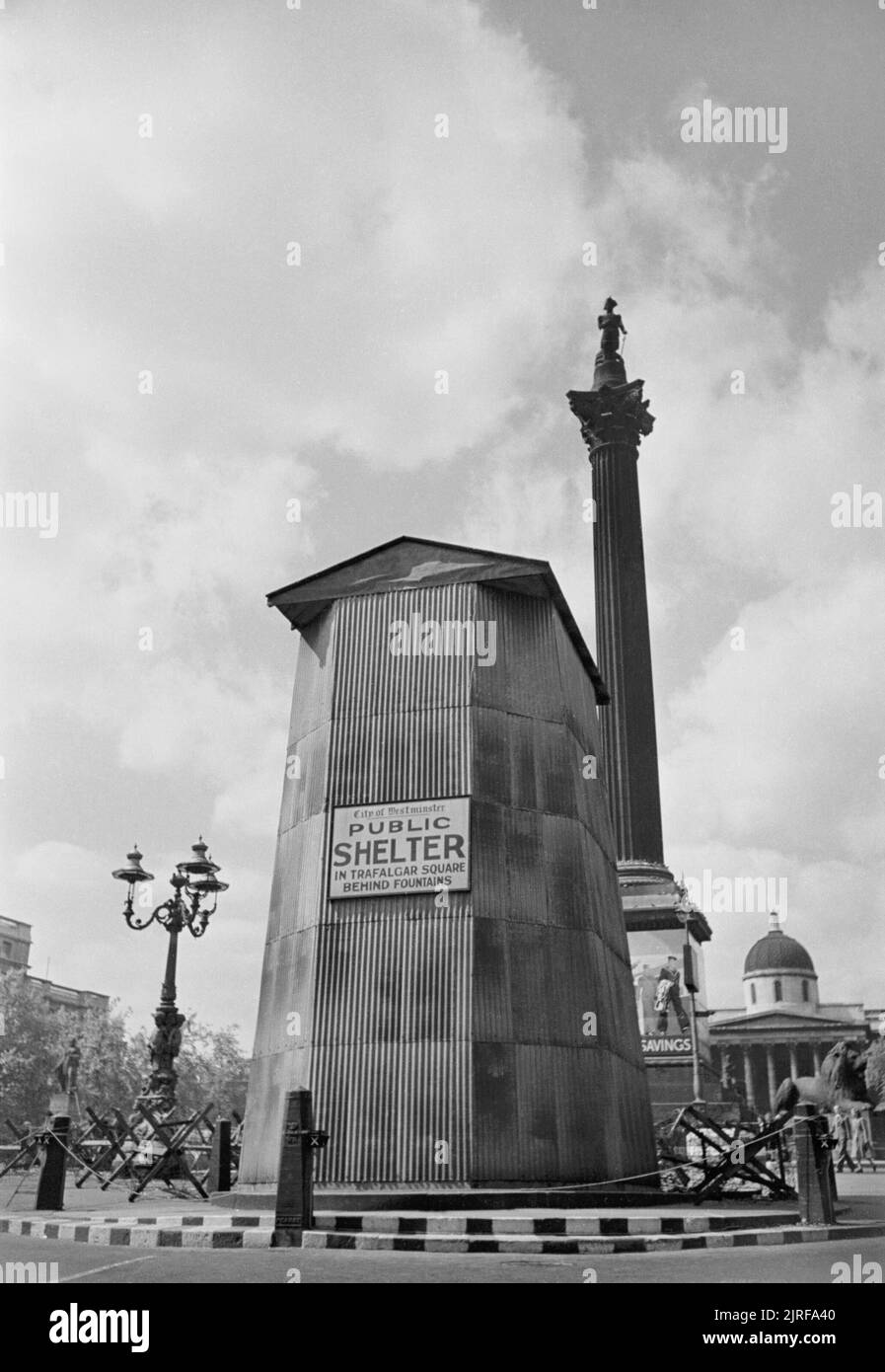 Air Raid Precautions in Central London, England, UK, 1941 A view of the King Charles I statue in Whitehall, showing the precautions taken to protect it from damage by air raids. The statue itself has been covered in a timber frame, sandbagged and then covered in corrugated iron. Clearly visible is a sign which directs people to the public air raid shelter in Trafalgar Square. Stock Photo