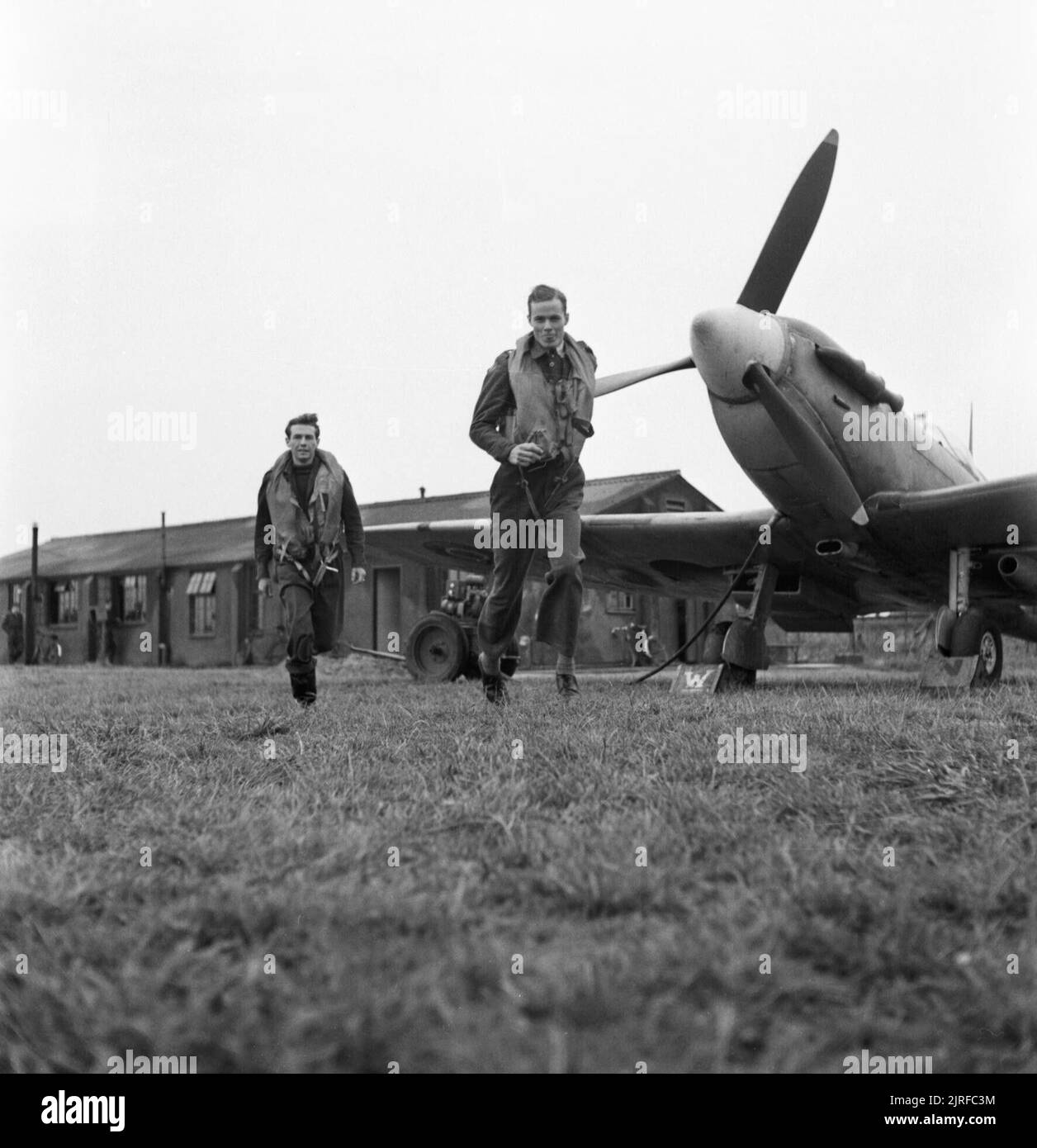 American volunteer pilots of No.121 (Eagle) Squadron run to their aircraft at RAF Rochford in Essex, August 1942. Flying Officer Barry Mahon (left) and Flight Lieutenant Seldon R Edner run to their aircraft as they are given the order to scramble. Both men are from California. The original caption states that enemy aircraft had appeared at 25,000 feet, seven miles south of the station, hence the need for action. Stock Photo