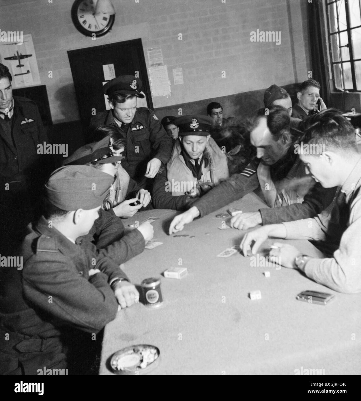 American volunteer pilots of No.121 (Eagle) Sqaudron playing poker in the dispersal hut at RAF Rochford in Essex during August 1942. In the Pilots' Dispersal Hut at Rochford airfield, personnel of No 121 (Eagle) Squadron play Poker as they await the order to 'scramble'. Left to right they are: Pilot Officer Beatie (standing, from Georgia), Pilot Officer Heppel (New Jersey), Pilot Officer Kearney (New Mexico), Flight Sergeant Blandy (South Carolina), Flight Sergeant Carpenter (standing, from Pennsylvania), Flight Officer Hasey (Oklahoma), Flight Sergeant Sanders (Tennessee) and Flight Sergeant Stock Photo