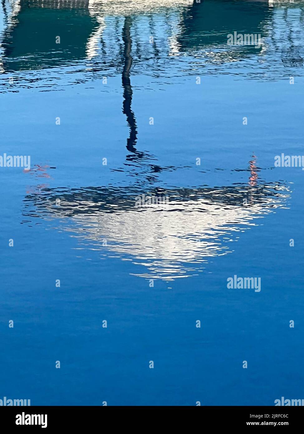 Beach umbrella reflecting on water surface. Rippled water surface. Summer vacation background with copy space. Stock Photo