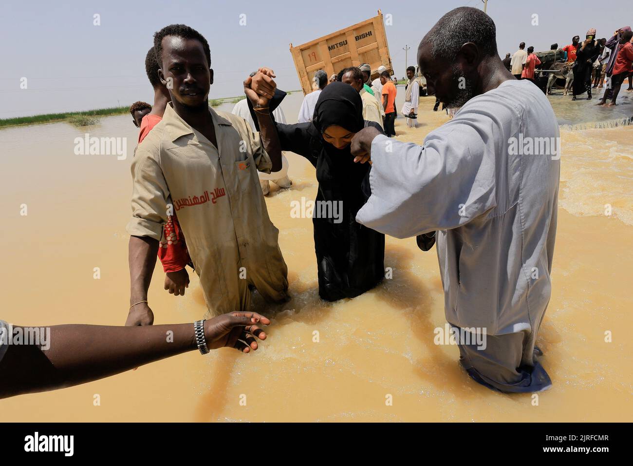 People cross the water during a flood in Al-Managil locality, Sudan, August 23, 2022. REUTERS/Mohamed Nureldin Abdallah Stock Photo