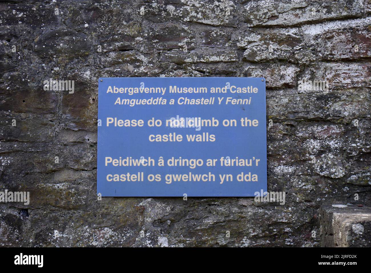 Sign in English and Welsh warning people not to climb on the castle walls, Abergavenny Castle, Wales, Inited Kingdom Stock Photo