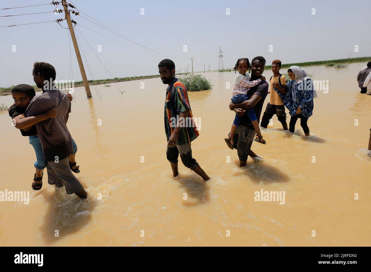 People cross the water during a flood in Al-Managil locality in Gezira state, Sudan, August 23, 2022. REUTERS/Mohamed Nureldin Abdallah Stock Photo