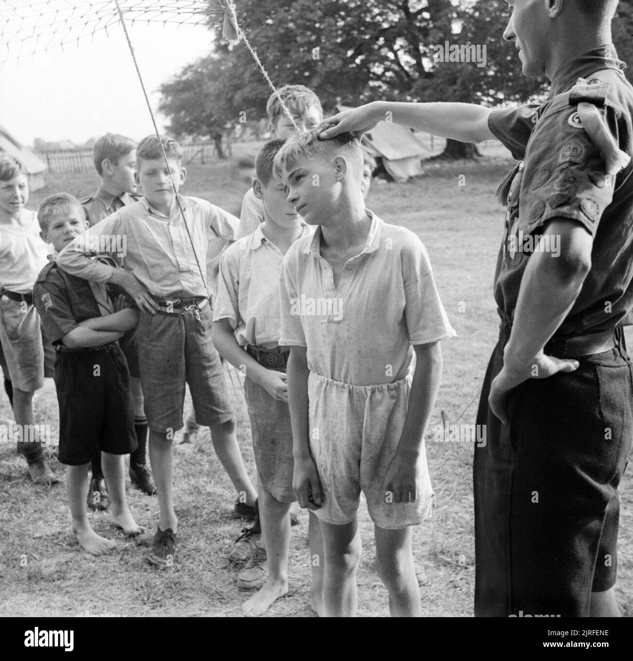 Boy Scouts queue up for their morning inspection at a fruit-picking camp near Cambridge in 1943. Boy Scouts queue up for their morning inspection at a fruit-picking camp near Cambridge. The Scout Leader checks their ears and necks to make sure they are clean before they set off for work in the plum orchards. Stock Photo