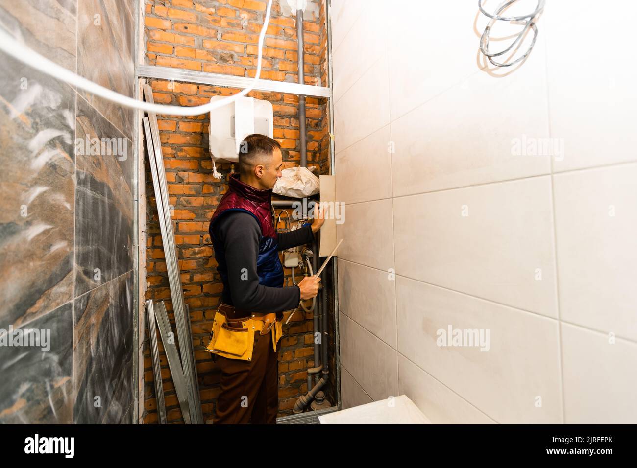 Laying Ceramic Tiles. Tiler placing ceramic wall tile in position over