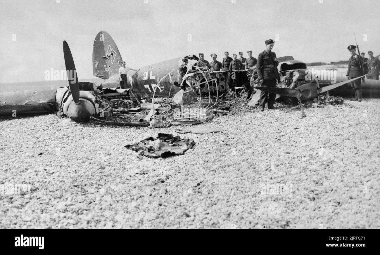 The Battle of Britain RAF personnel examine the wreck of Heinkel He 111H (G1+LK) of 2./KG 55 on East Beach, Selsey in Sussex, shot down by P/O Wakeham and P/O Lord Shuttleworth of No. 145 Squadron, 11 July 1940. Stock Photo