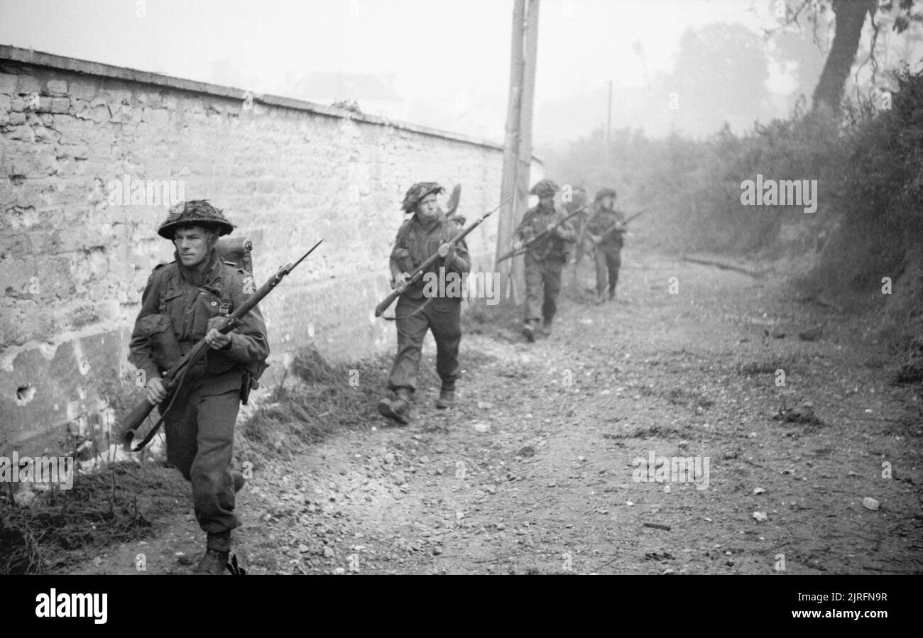Men of 12 Platoon, 'B' Company, 6th Royal Scots Fusiliers advance into St Manvieu during Operation 'Epsom', Normandy, 26 June 1944. Men of 12 Platoon, 'B' Company, 6th Royal Scots Fusiliers advance into St Manvieu during Operation 'Epsom', 26 June 1944. Stock Photo
