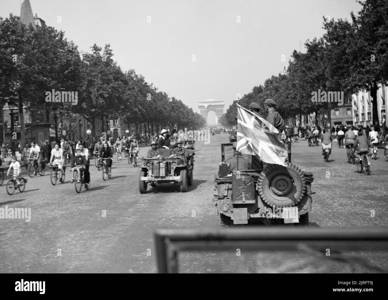An AFPU (Army Film and Photographic Unit) jeep displaying a large union flag drives down the Champs Elysees in Paris, 26 August 1944. An AFPU jeep displaying a large union flag drives down the Champs Elysees in Paris, 26 August 1944. Stock Photo