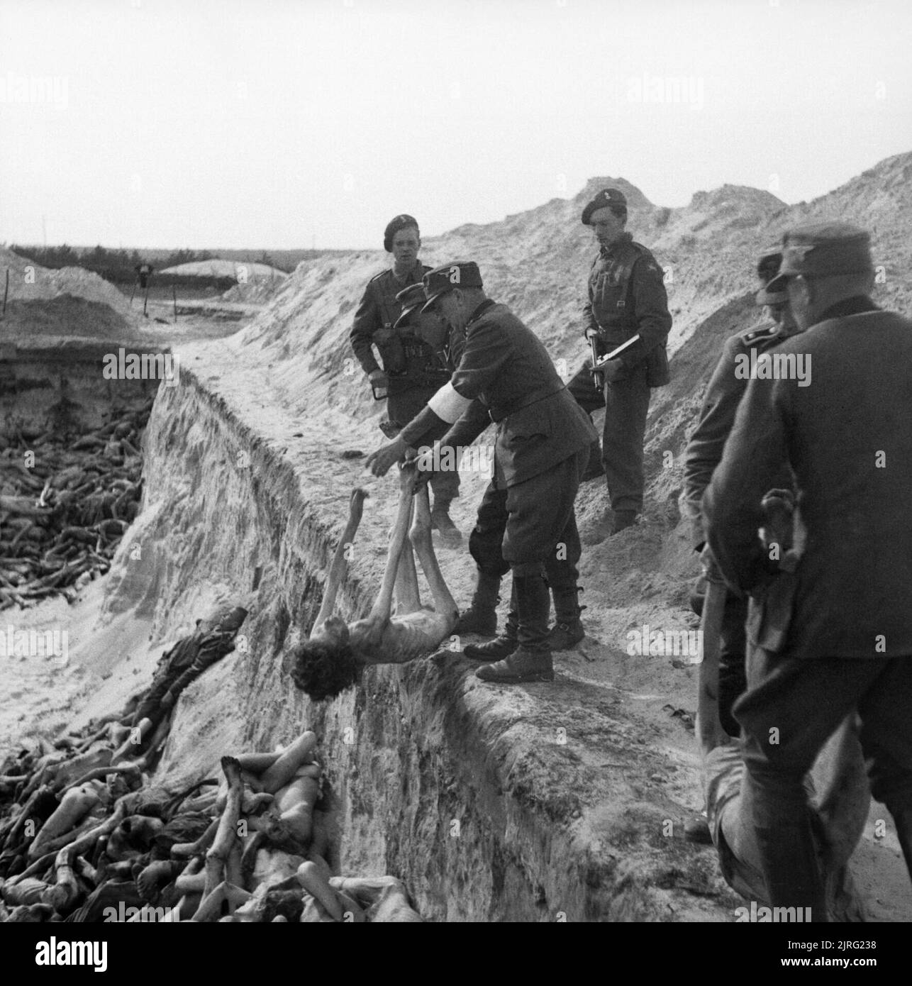 The Liberation of Bergen-belsen Concentration Camp, April 1945 German SS guards toss the body of a dead girl into a mass grave. Stock Photo