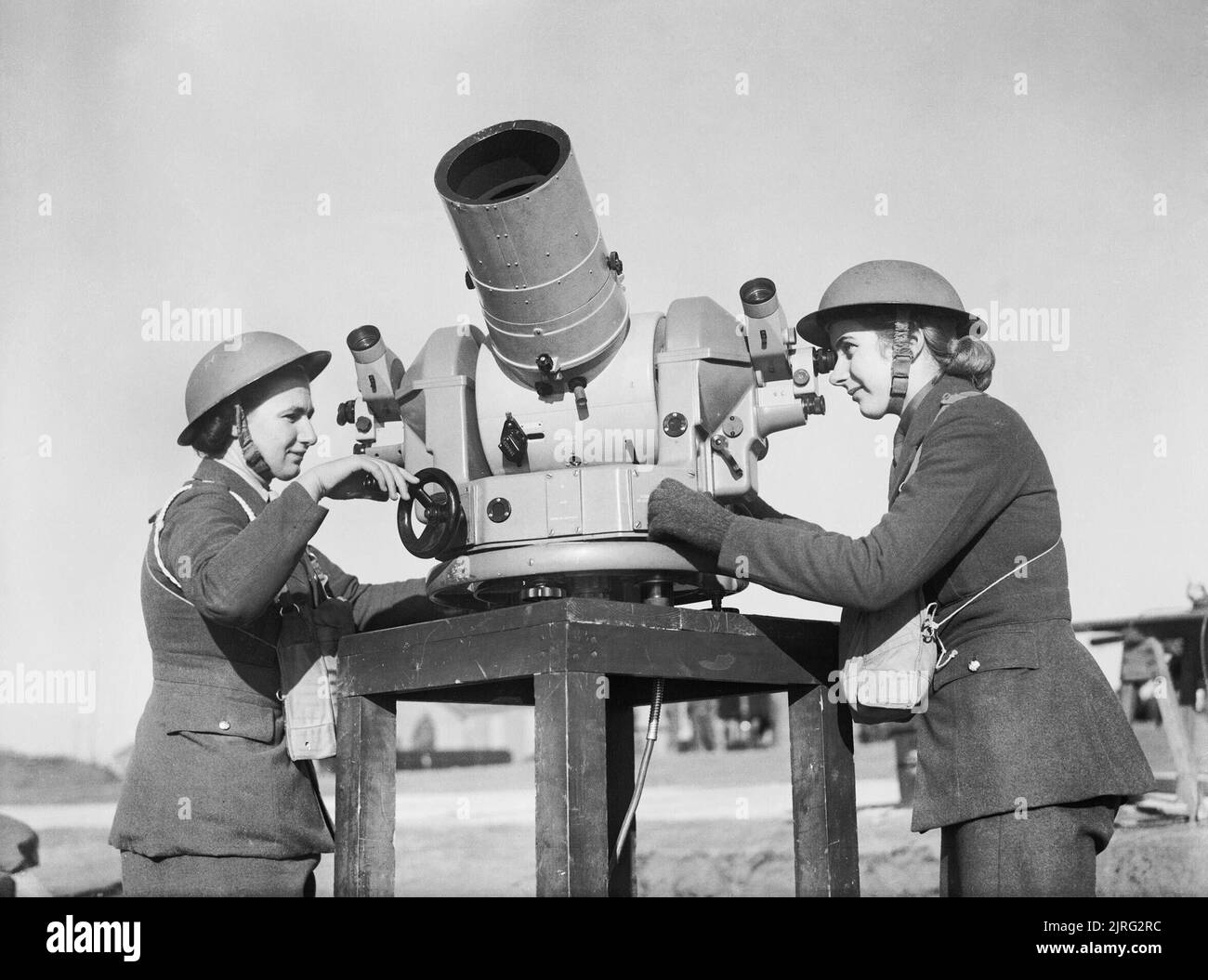 Two members of the Auxiliary Territorial Service (ATS) check the accuracy of anti-aircraft fire from a gun battery during the Second World War. The Auxiliary Territorial Service (ATS): Using a Kine-Theodolite - an instrument which records on film the bursts of anti-aircraft shells - two ATS women check the accuracy of the firing at an AA Battery at Manorbier. Stock Photo