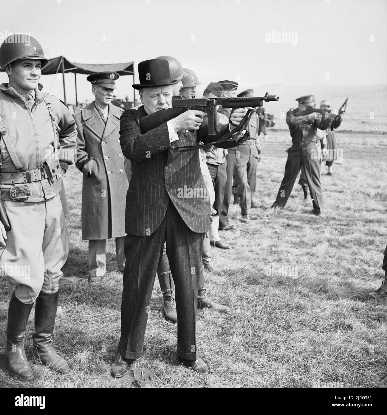 Winston Churchill fires a Thompson submachine gun alongside the Allied Supreme Commander, General Dwight D Eisenhower, during an inspection of US invasion forces, March 1944. The Prime Minister Winston Churchill fires a Thompson 'Tommy' submachine gun alongside Supreme Allied Commander of the Allied Expeditionary Force General Dwight D Eisenhower as American soldiers look on in southern England in late March 1944. Stock Photo