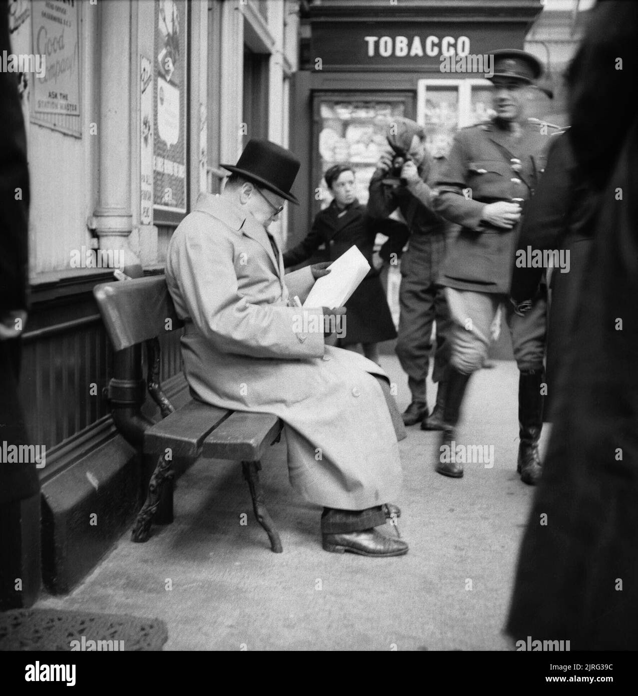 Winston Churchill reads a newspaper on the platform at St Andrews railway station, during a tour of defences and naval forces in Scotland, 23 October 1940. The Prime Minister Winston Churchill reads a newspaper on the platform while waiting for a train at St Andrews during a trip to Scotland to visit Polish troops, inspect coastal defences and tour a Naval Establishment in Fife on 23 October 1940. Stock Photo