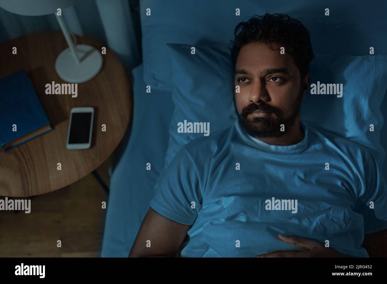 speelpess indian man lying in bed at night Stock Photo