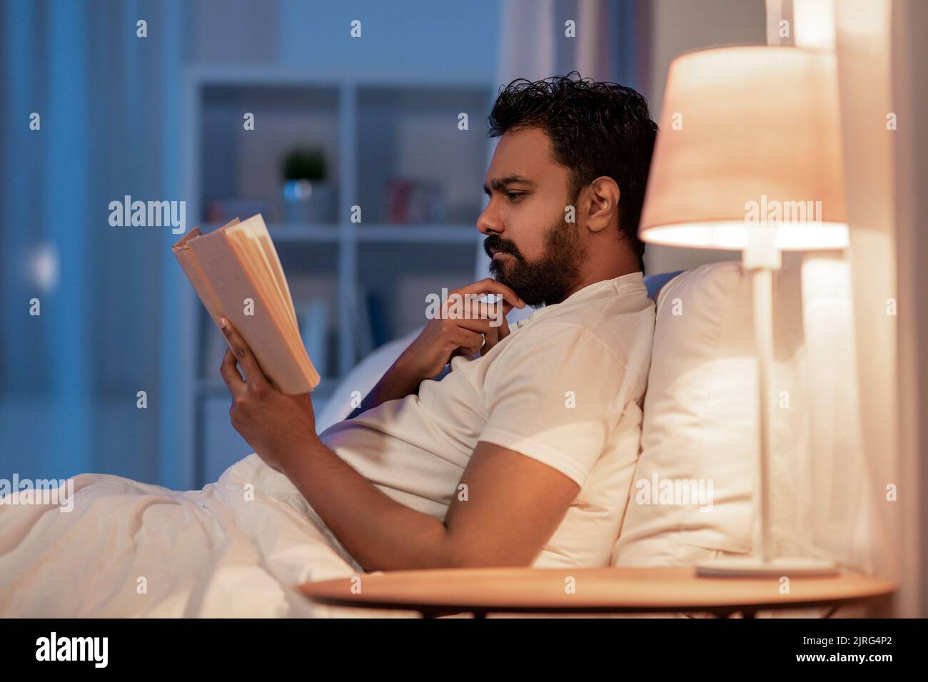 indian man reading book in bed at night Stock Photo Alamy