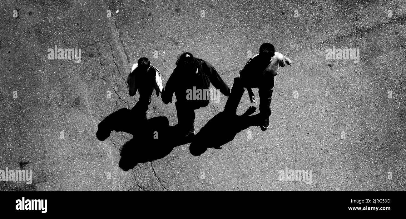 Several people walking down below on concrete with shadows aerial view from above Stock Photo