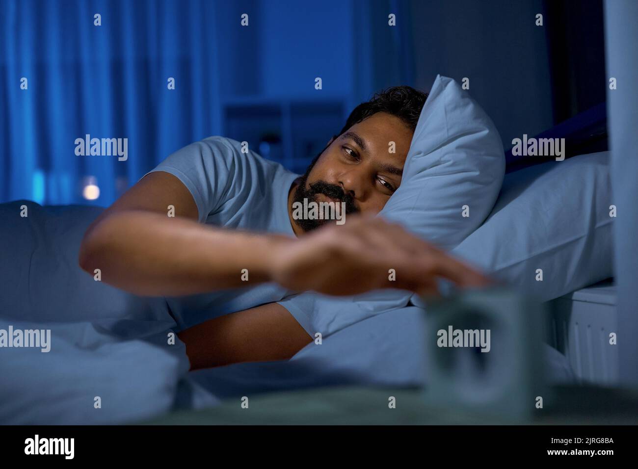 indian man awaking because of alarm clock at night Stock Photo