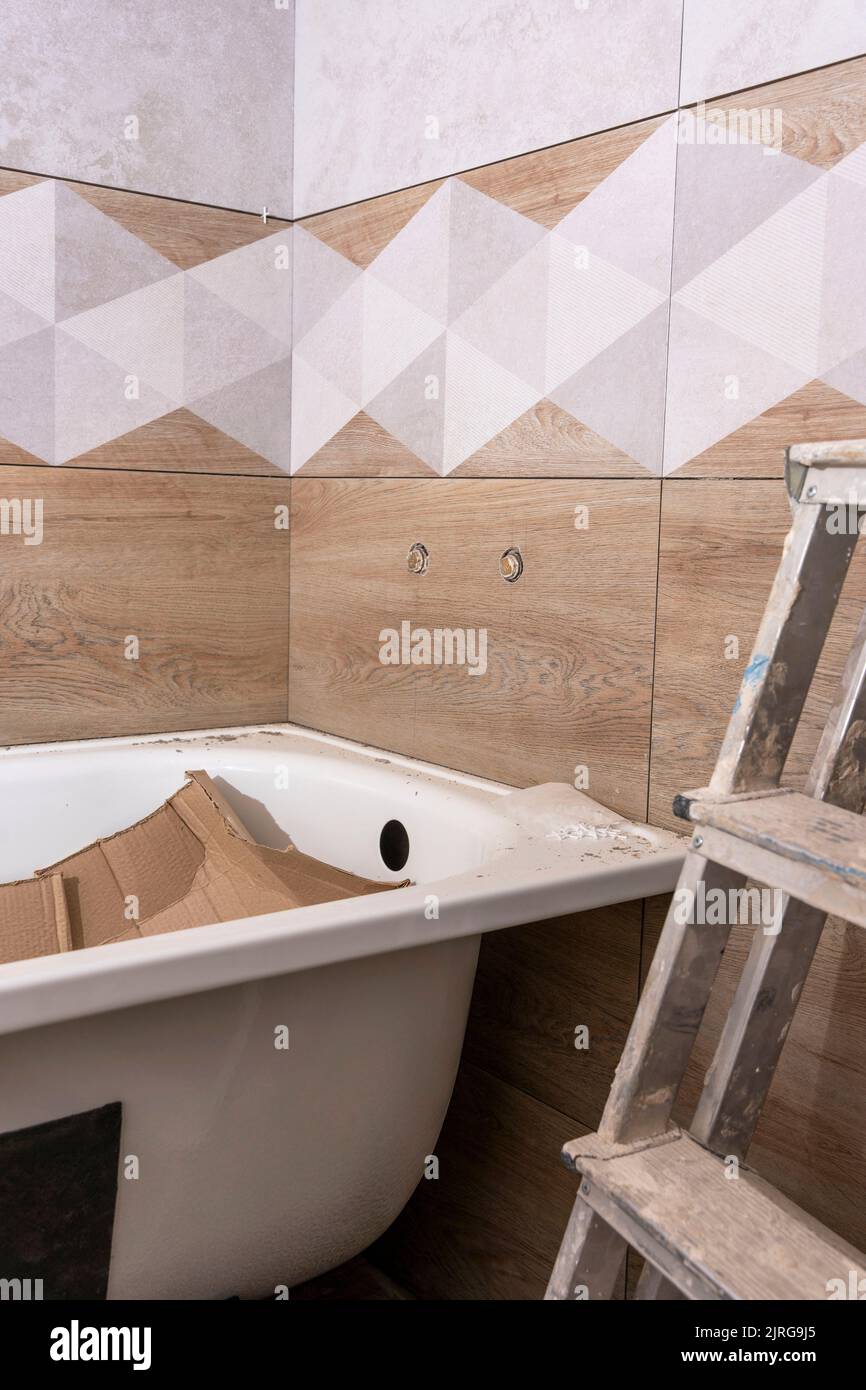 installing a new bathtub and laying ceramic tiles in bathroom. Repair Stock Photo