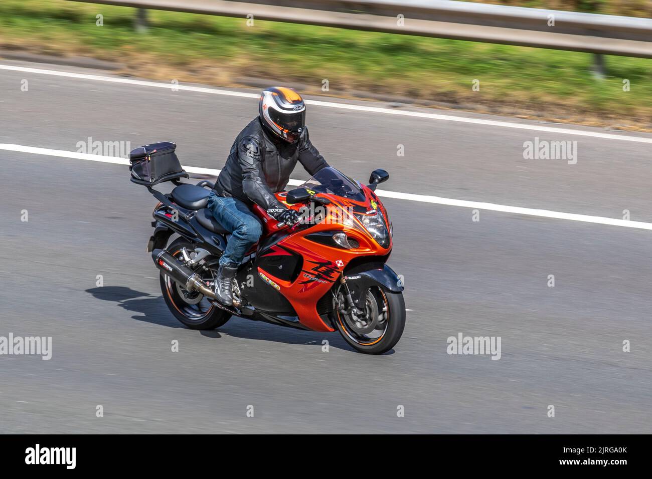 Orange Suzuki Hayabusa GSX1300R super bike; moving, being driven, in motion, travelling on the M6 motorway, UK Stock Photo