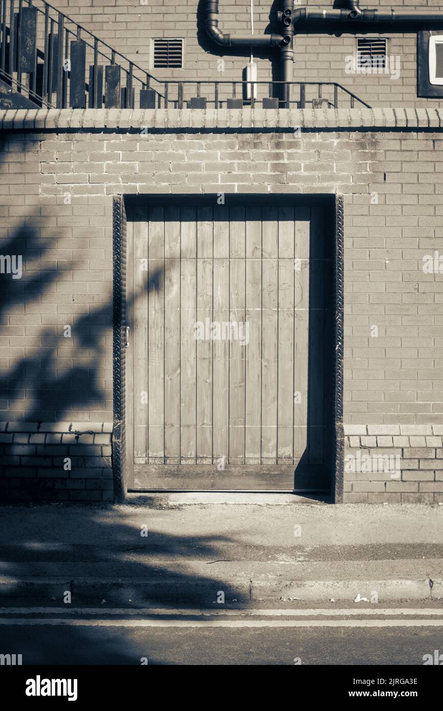 A monochrome image of a wooden doorway in an urban area. Stock Photo