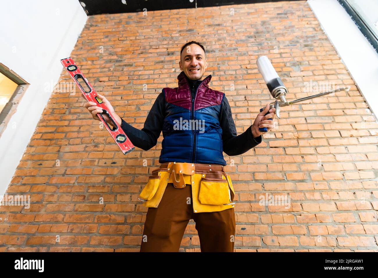 Closeup of bricklayer hands holding hardhat and construction equipment