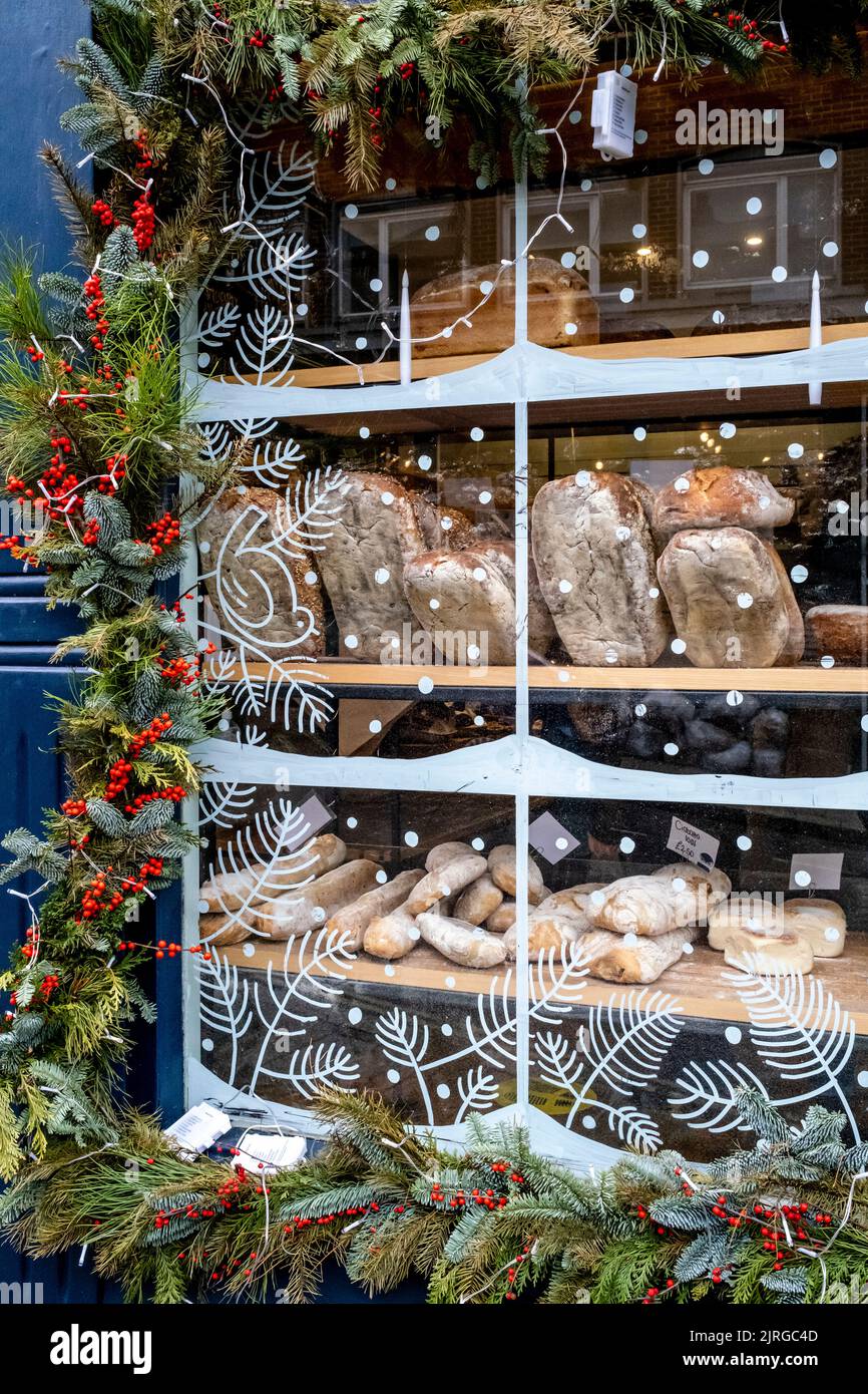 The Window Of A Bakery Is Decorated with Holly At Christmas Time, High Street, Lewes, East Sussex, UK. Stock Photo