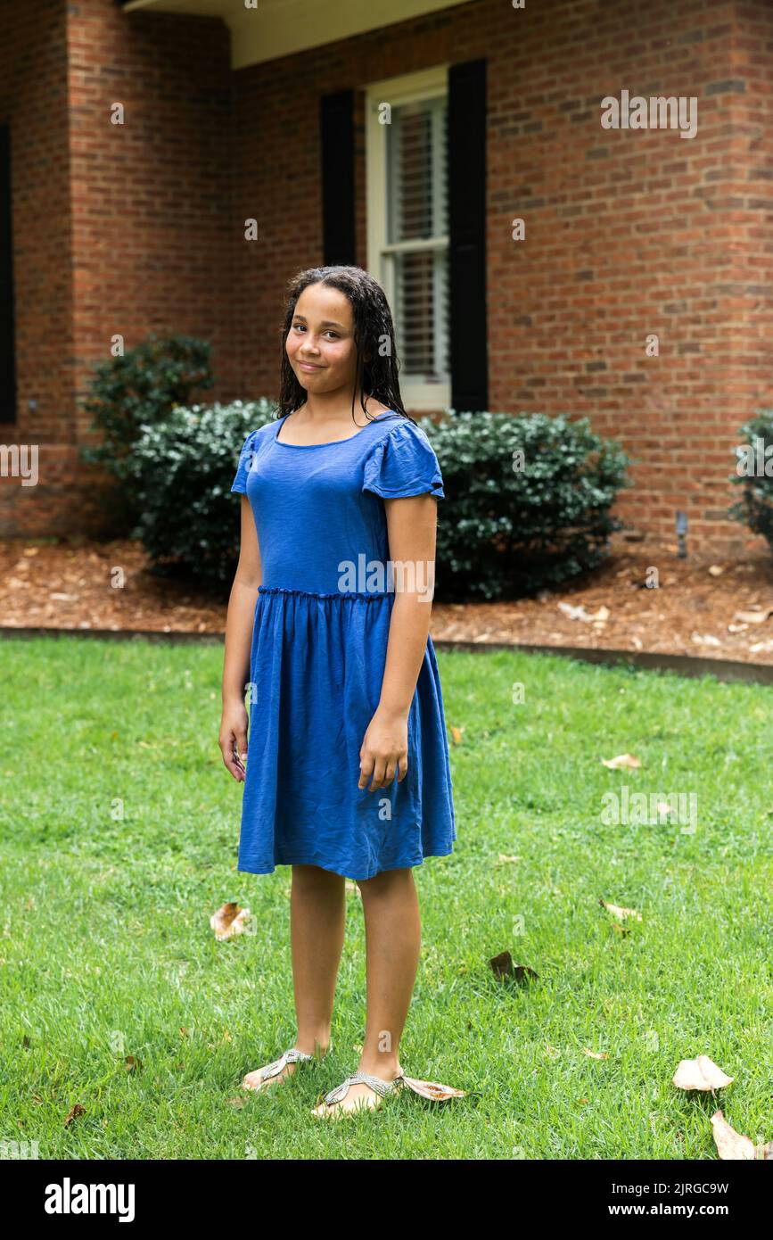 Middle School aged girls in a blue dress standing outside her home for a portrait Stock Photo