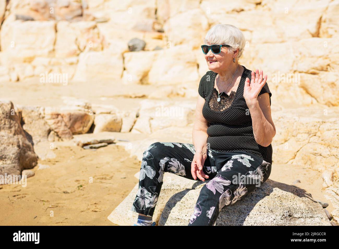 Old woman in black clothes sitting on a rock near the sea Stock Photo ...