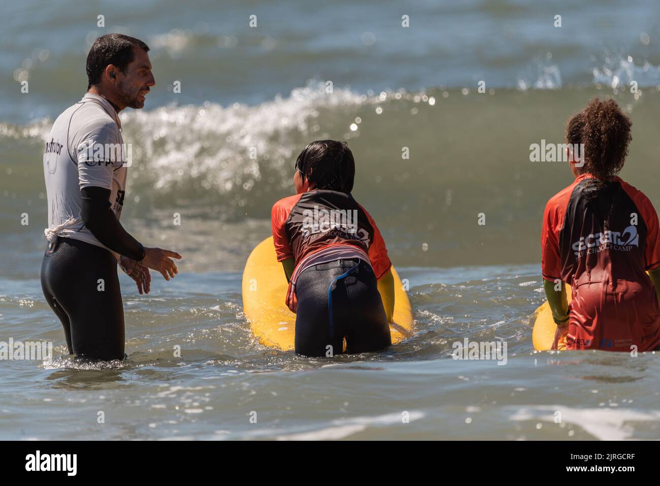 Aveiro, Portugal - August 19, 2022: A group of children practice with a surf instructor on the beach. Stock Photo