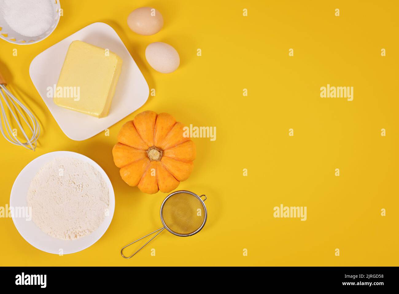 Pumpkin pie ingredients and baking tools on yellow background with copy space Stock Photo