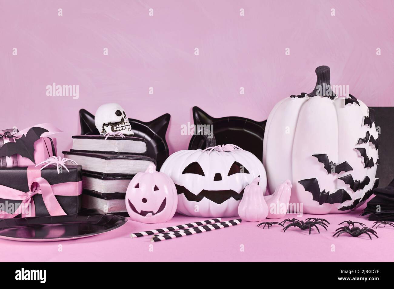 Pink Halloween decor with black and white pumpkins, spell books and