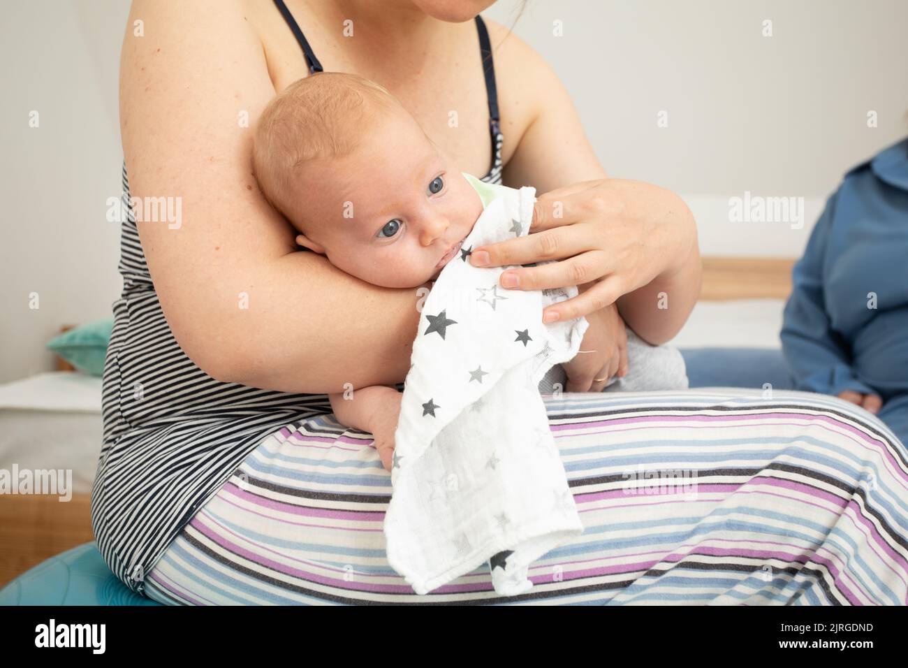 Mother holding and rocking baby sitting on fitball Stock Photo