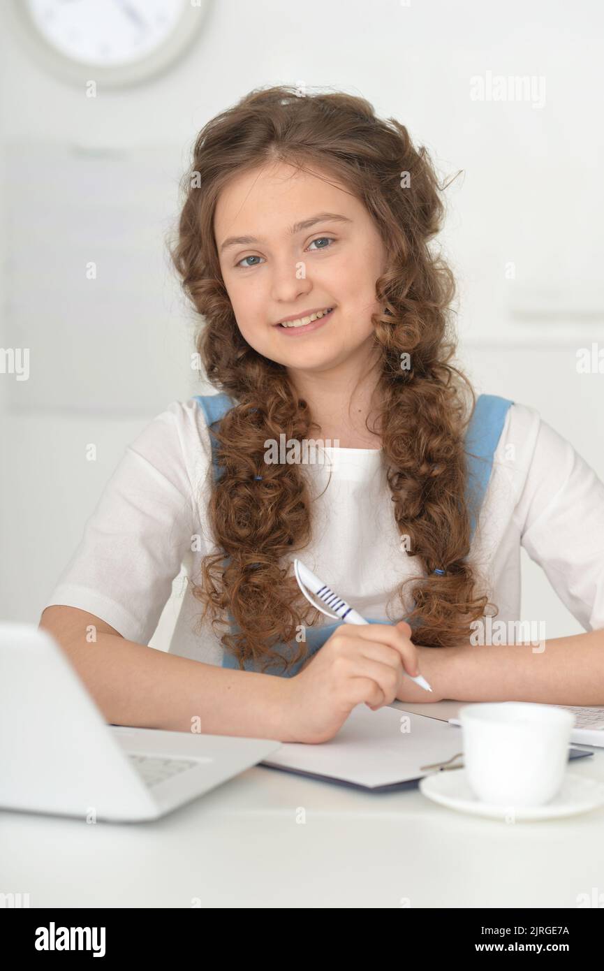 Cute schoolgirl doing home work with laptop in the room Stock Photo - Alamy