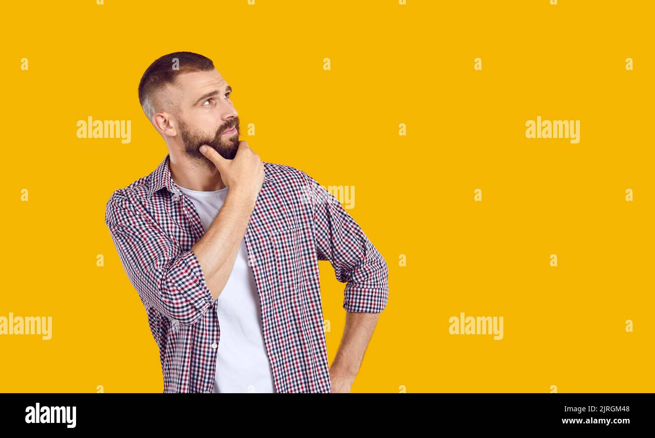 Man standing isolated on yellow background, looking at copy space and thinking about something Stock Photo