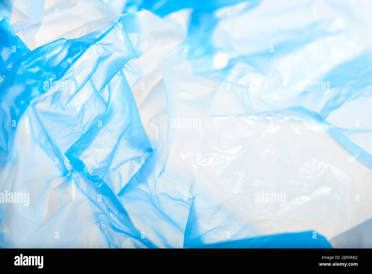 White and blue plastic background, wrinkled single use bag. Concepts: sustainability, recycling, pollution. Stock Photo