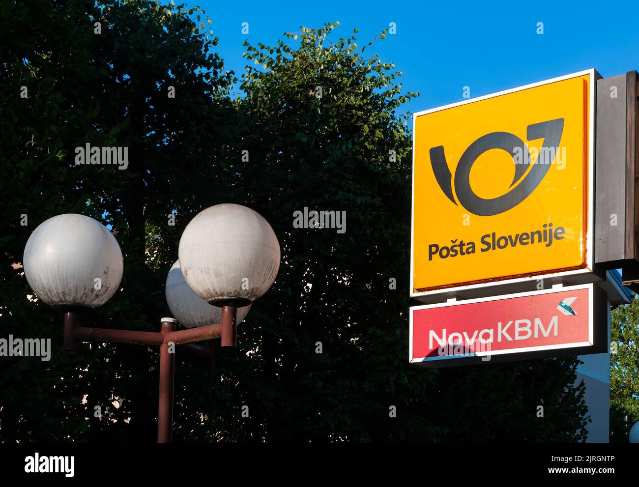 Domzale, Slovenia - August 3, 2022: Street lamp and a signboard with emblem of slovenian national post Stock Photo