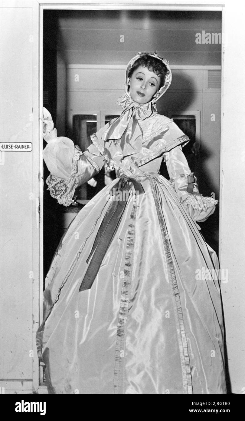 LUISE RAINER candid portrait at door of dressing room wearing gown by GILBERT ADRIAN during filming of THE GREAT WALTZ 1938 director JULIEN DUVIVIER Metro Goldwyn Mayer Stock Photo