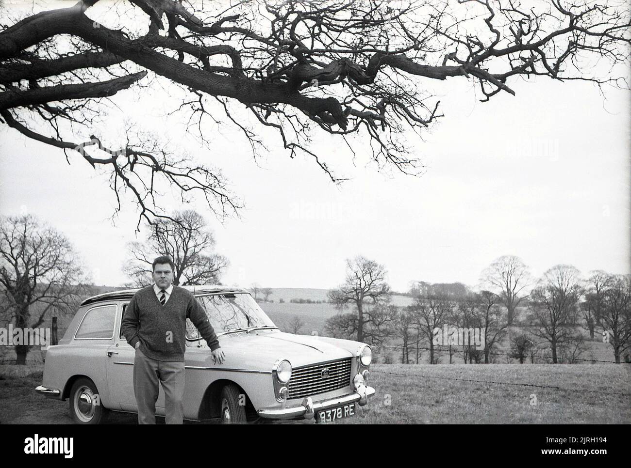 1958, historical, outside in the countryside, on a small farm lane, a man standing by an Austin A40 Farina car of the era, England, UK. A modern small car, with a distinctive 'two box' shape and headroom in the back seat, it was a look created by notable Italian automobile designer Battista Farina, famous for his work with Ferrari and the Alfa Romeo Spider. The car was produced up to 1967, when it was succeeded by the Austin 1100. Stock Photo