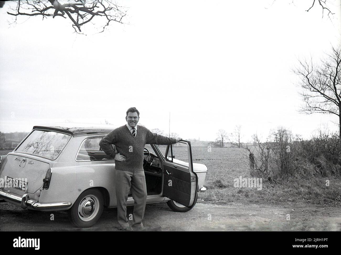 1958, historical, outside in the countryside, on a small farm lane, a man standing by an Austin A40 Farina car of the era, England, UK. A modern small car, with a distinctive 'two box' shape and headroom in the back seat, it was a look created by notable Italian automobile designer Battista Farina, famous for his work with Ferrari and the Alfa Romeo Spider. The car was produced up to 1967, when it was succeeded by the Austin 1100. Stock Photo