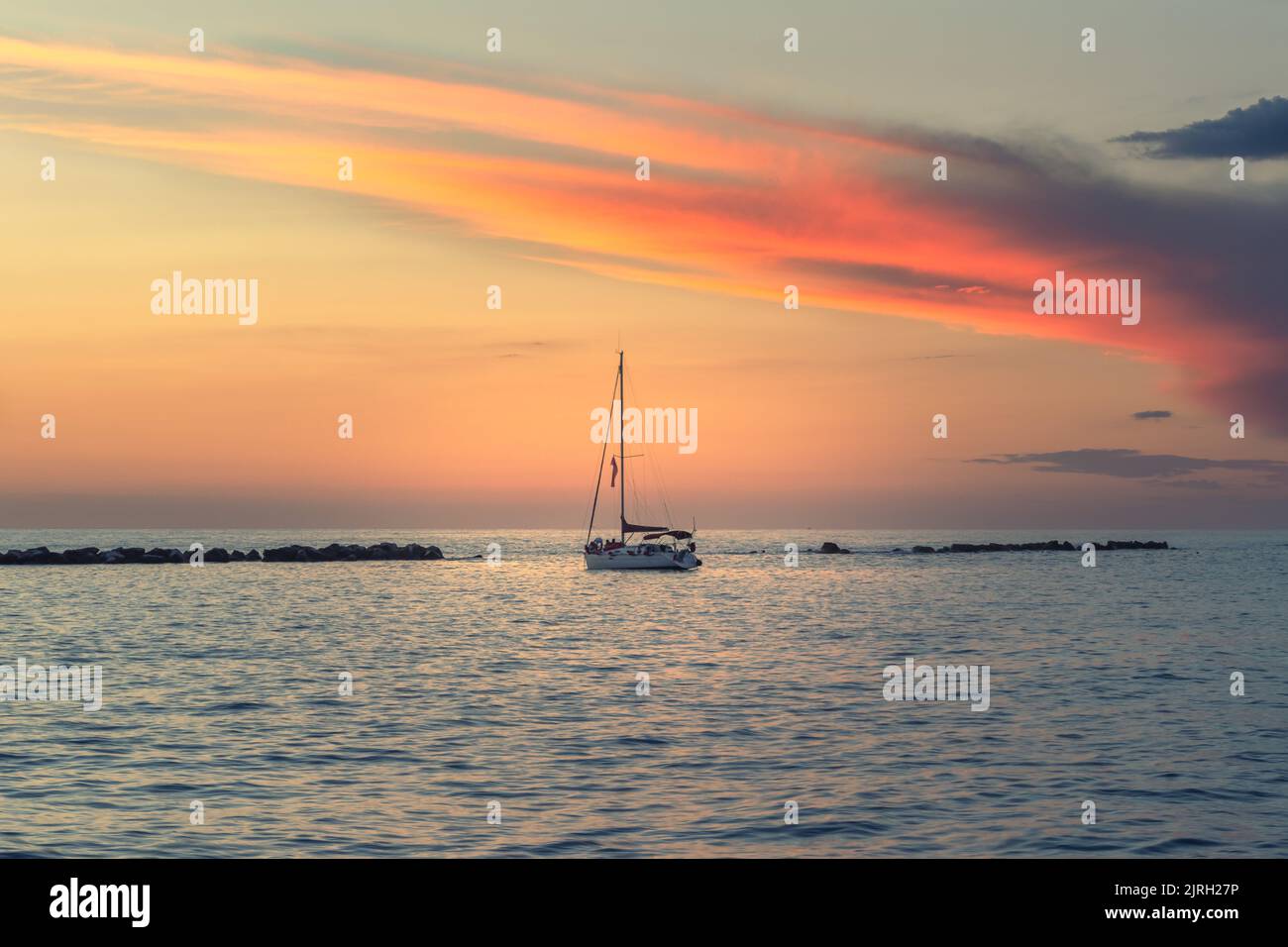 red sunset clouds over a sailing boat at the sea in Anzio, Rome, Italy Stock Photo