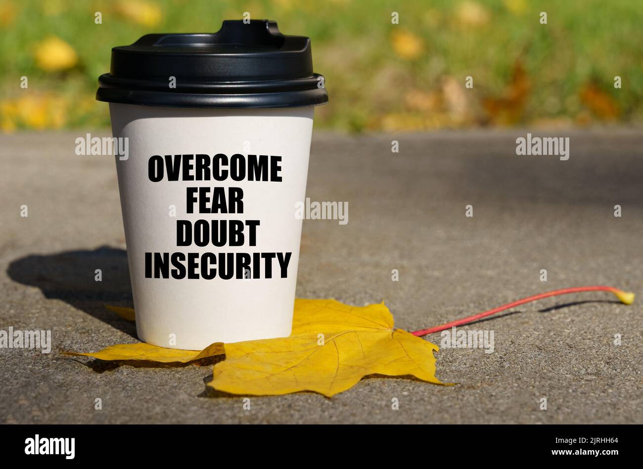 On a yellow maple leaf there is a cup of coffee on which is written - overcome fear, doubt, insecurity. Business concept. Stock Photo