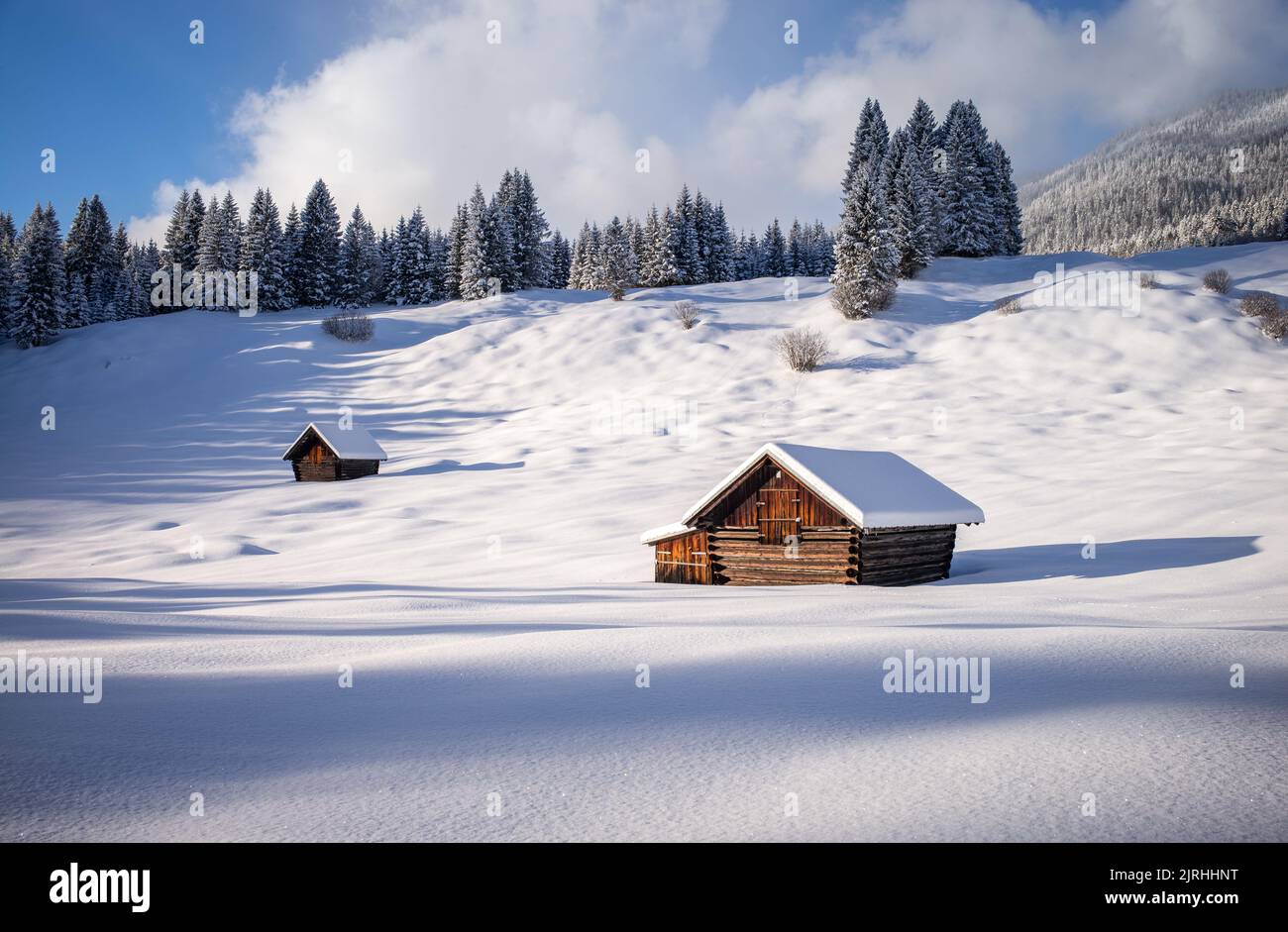 Verschneite Holzhütten auf einer Buckelwiese, Bayern, Deutschland Stock Photo