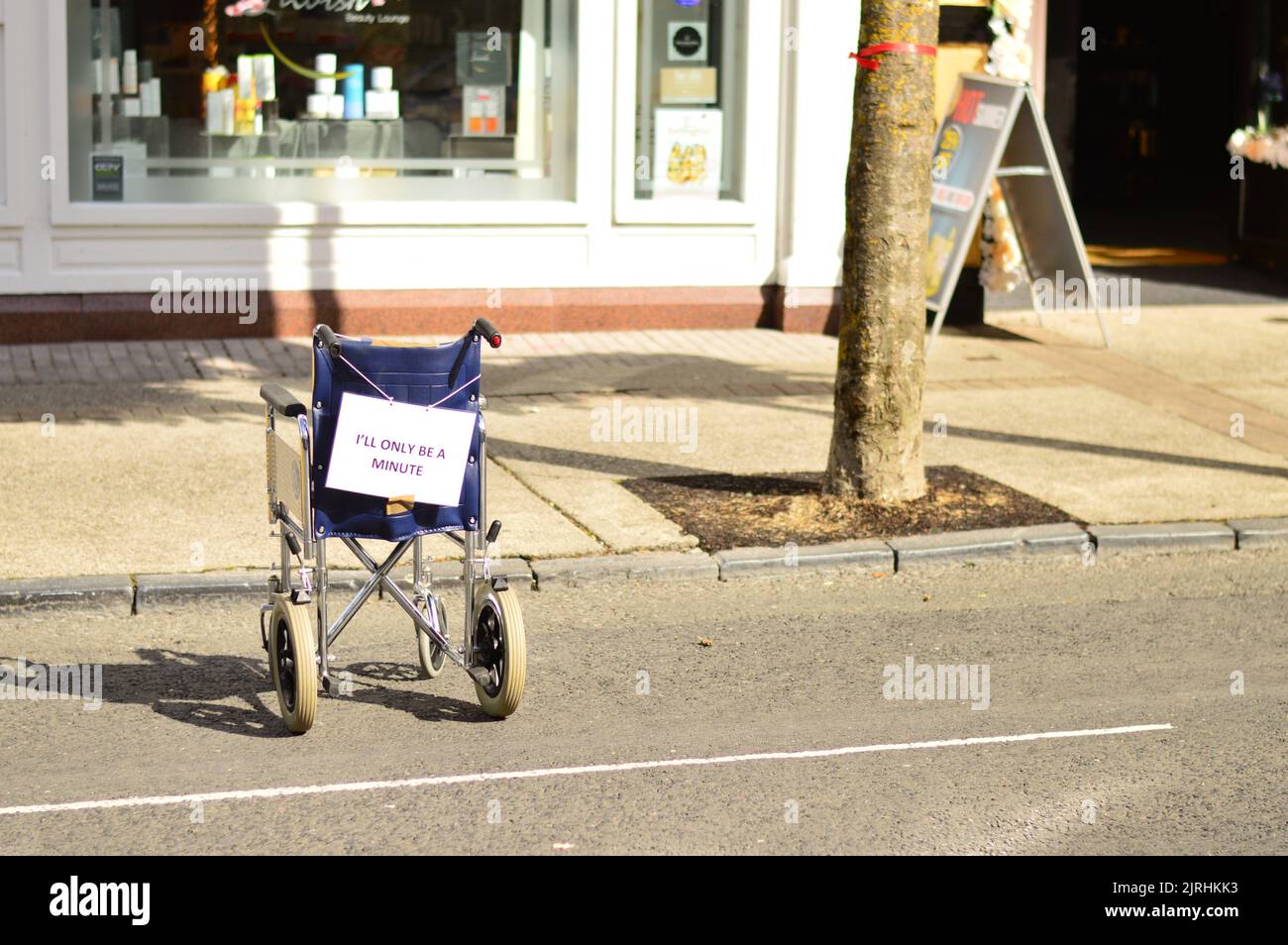 'Back in 5' campaign shows wheelchair in car parking space at protest of car drivers parking in disabled bays Stock Photo