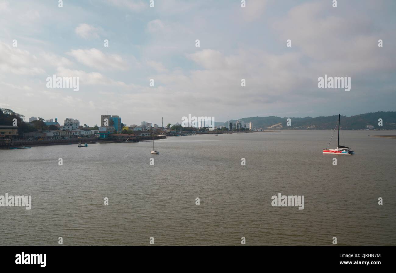 Bahia de Caraquez, Manabi / Ecuador - August 20 2022: Boats sailing on the Chone river with a panoramic view of the city in the background during suns Stock Photo