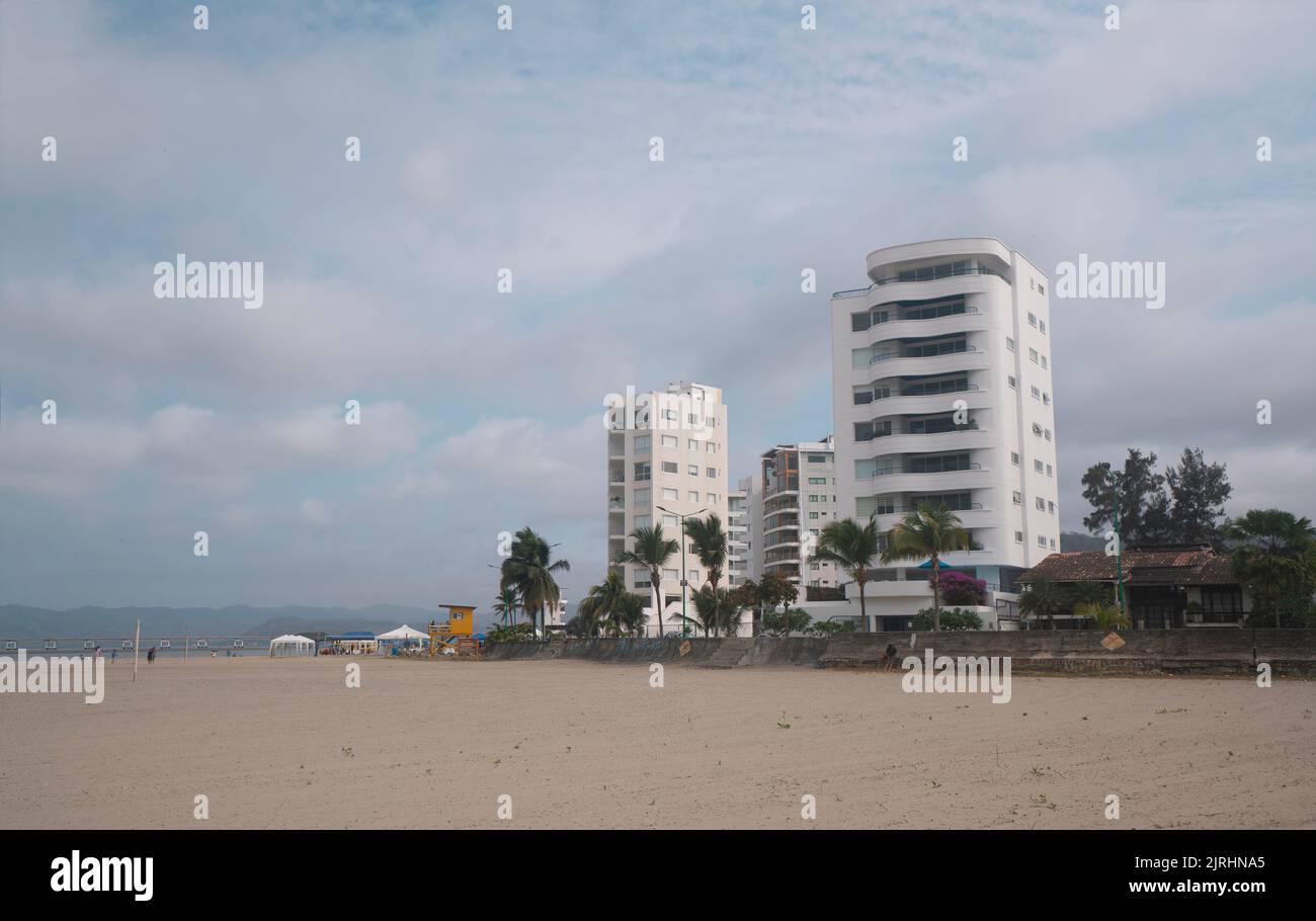 Bahia de Caraquez, Manabi / Ecuador - August 19 2022: People walking and playing on the beach in front of the boardwalk with modern condominiums in th Stock Photo