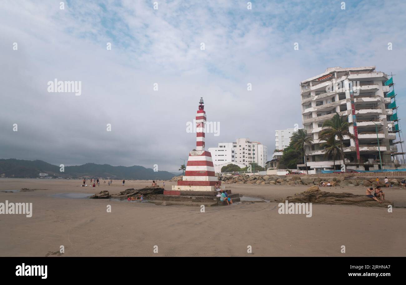 Bahia de Caraquez, Manabi / Ecuador - August 19 2022: People walking and resting near the lighthouse on the beach in front of the boardwalk with moder Stock Photo