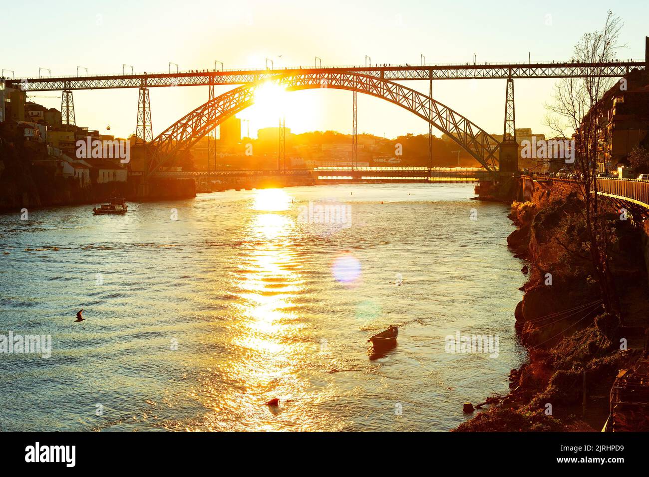 Sunset view of Douro river with boats and Dom Luis bridge in bright sunlight, Porto, Portugal Stock Photo