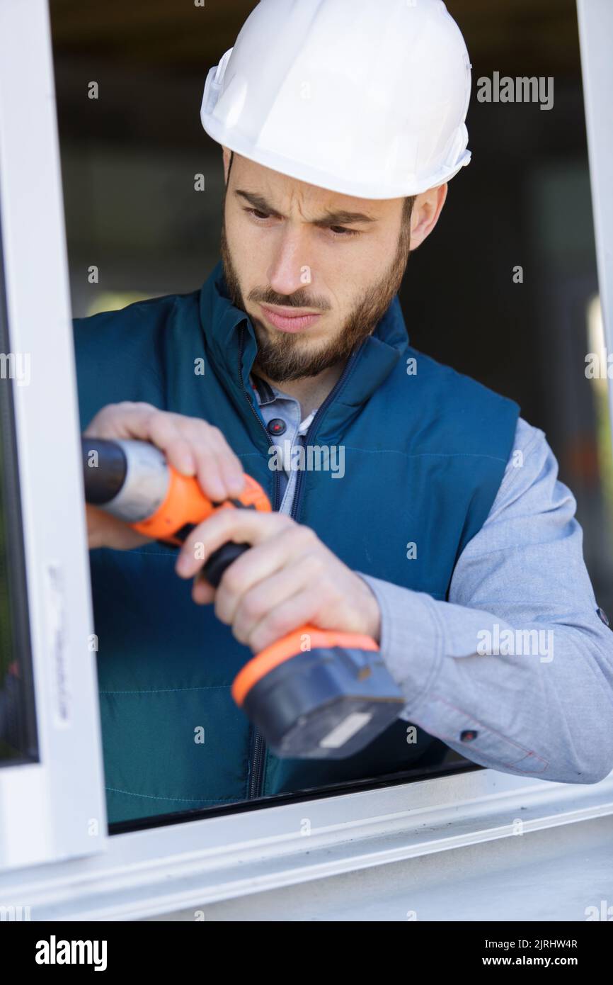 male fitter using cordless powertool on window frame Stock Photo Alamy