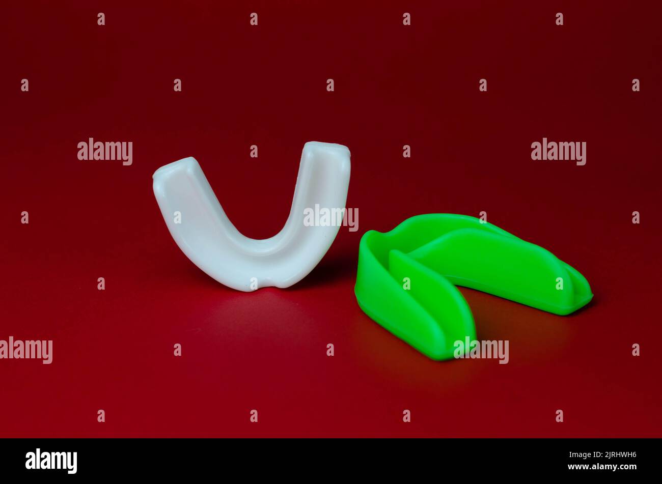 two rubber boxing mouth guards, white and green, protection for lips