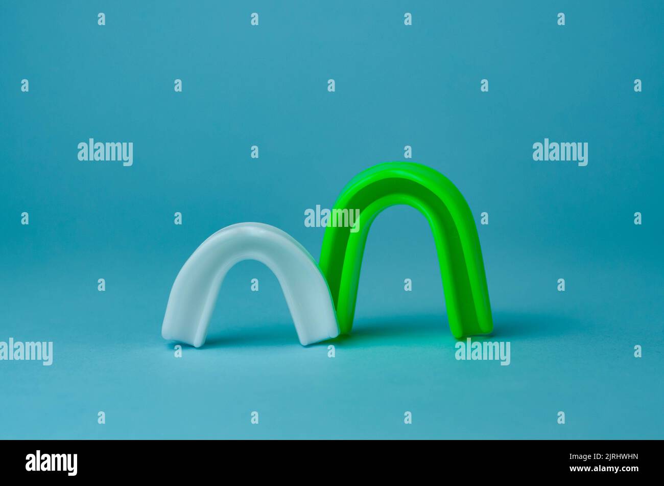 two rubber boxing mouth guards, white and green, protection for lips