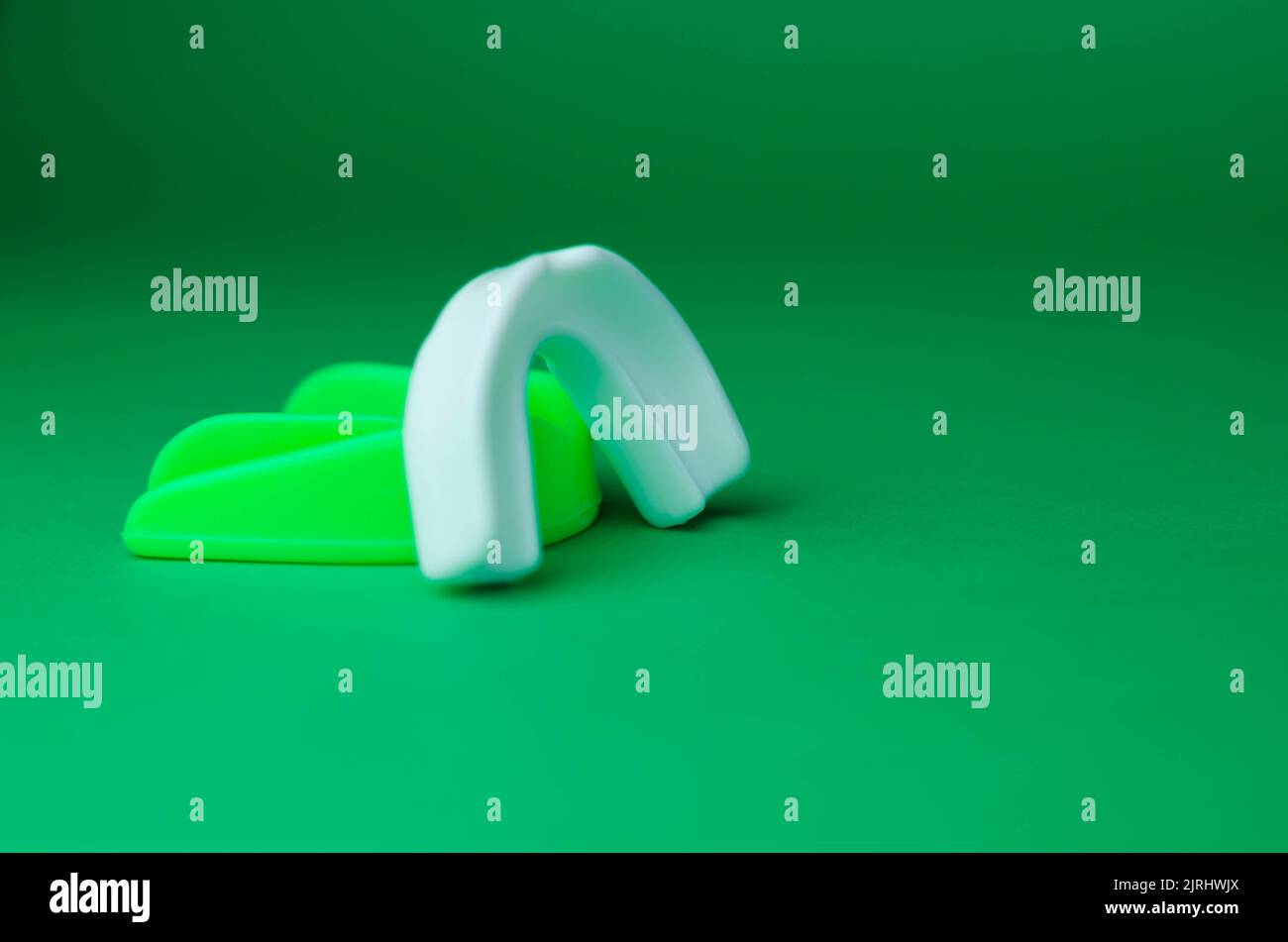 two rubber boxing mouth guards, white and green, protection for lips